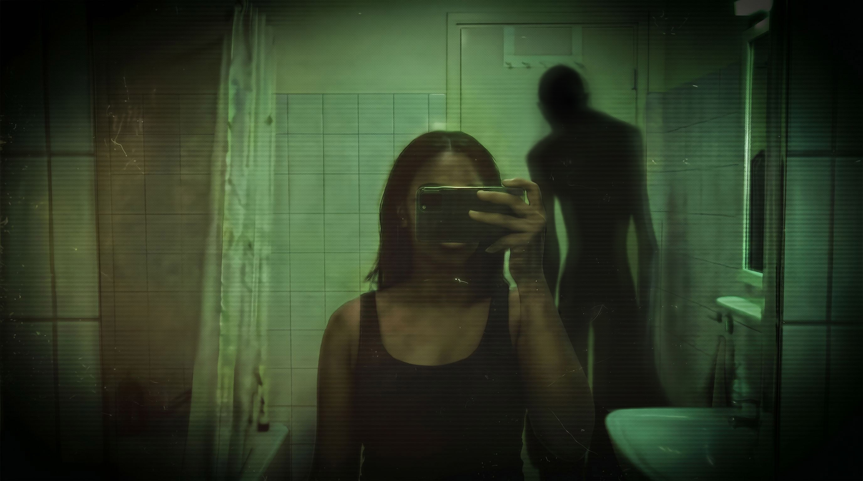 A person photographing themselves in a mirror with a shadowy figure standing behind them